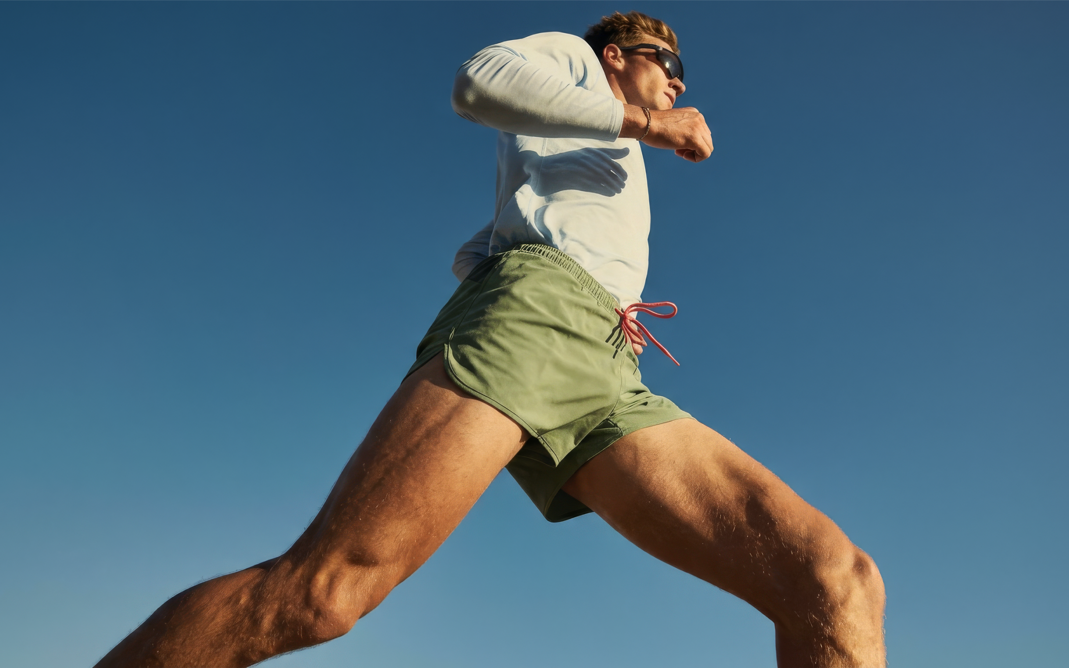 Athlete running beneath a clear blue sky